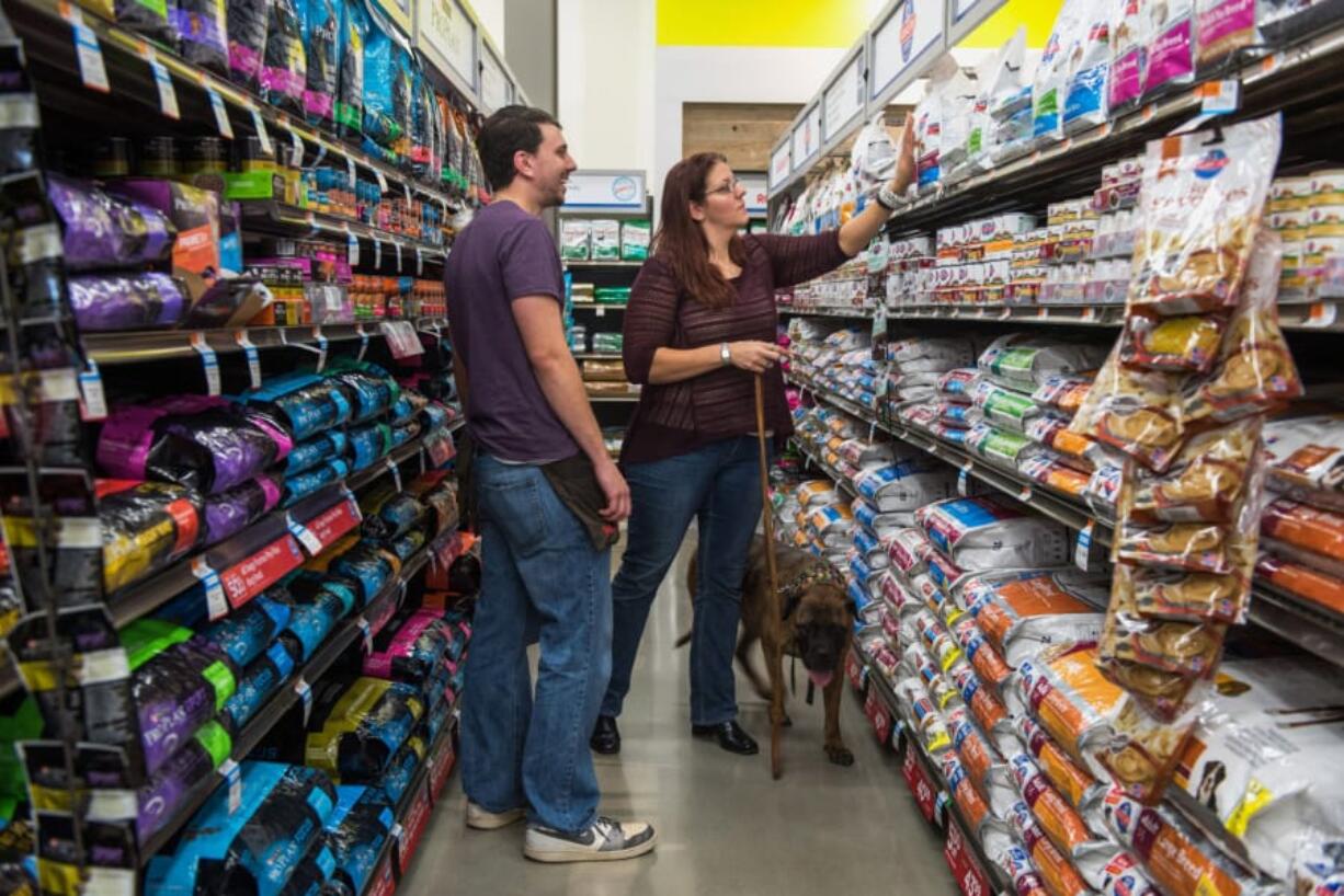 An employee assists a customer with dog food at a Petco store in Clark, N.J., in 2015.