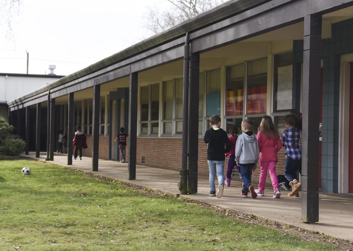 Students at Glenwood Heights Primary School walk down a covered walkway to a classroom in March 7. The school, which was built in 1956, has many outdoor classroom entrances, which Battle Ground Public Schools says poses a safety concern. The district is seeking approval of a $224.9 million bond issue in an April 24 special election.