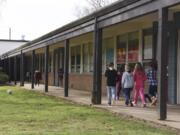 Students at Glenwood Heights Primary School walk down a covered walkway to a classroom in March 7. The school, which was built in 1956, has many outdoor classroom entrances, which Battle Ground Public Schools says poses a safety concern. The district is seeking approval of a $224.9 million bond issue in an April 24 special election.