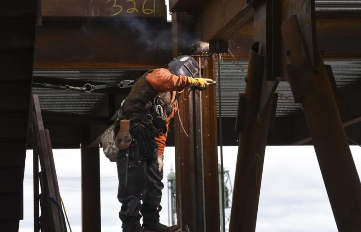 A welder works on a brace frame on the sixth floor of the seven-story office tower at the Vancouver waterfront in March. An upsurge in construction positions helped drive a 400-job increase in seasonally adjusted Clark County employment in March.