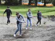 Coach Joe Cain, left, watches at Battle Ground High School golfers Grace Ritola, Jessica Spalding and Reilly Joma practice at The Cedars on Salmon Creek. The course sold 30 acres to a real estate developer last year in the hopes of landing more neighbors and business.