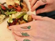 Jenelle York’s fruit and veggie tattoos are on display while she eats a roasted vegetable flatbread at Bleu Door Bakery.