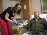 Christina Gay, left, administers medication to Gene Wickstrom of Cathlamet during the April 5 night shift at Legacy Salmon Creek Medical Center in Vancouver. Gay’s class at Hough Elementary School was tapped for the local I Have a Dream program in 1997 and she studied nursing at Clark College and Washington State University Vancouver.