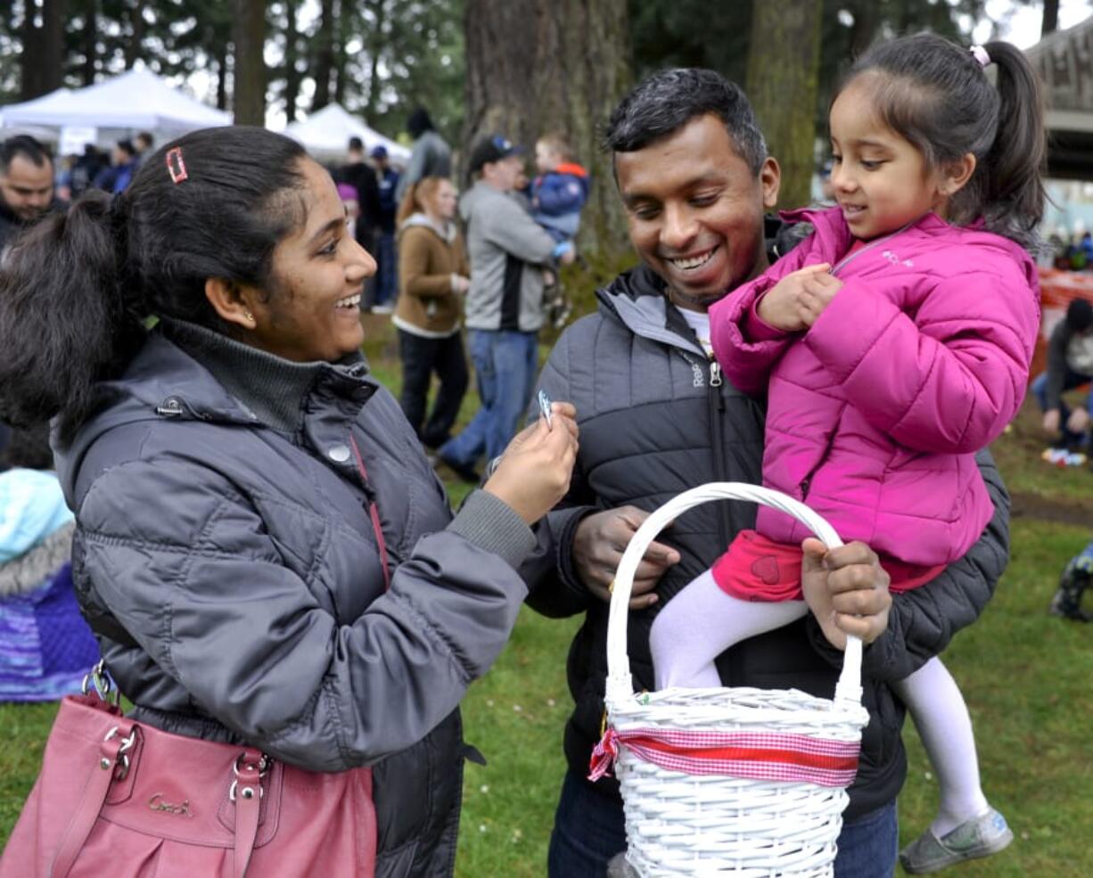 Mahi Bagal, left, and Mahesh Bagal check out their daughter Tenishka’s prizes Sunday after the Easter Egg Hunt at Crown Park in Camas.