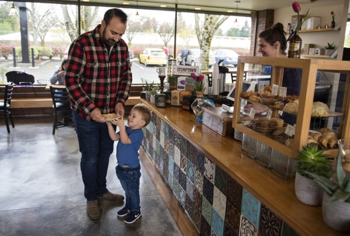 After closing up shop on Devine Road in June, River Maiden Artisan Coffee is back up and running at a new location — 5301 E. Mill Plain Blvd. — in Vancouver. Adam Hendrix of Vancouver, left, and his son, Cal, 3, stop by the new shop for a treat on Monday morning.