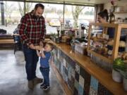 After closing up shop on Devine Road in June, River Maiden Artisan Coffee is back up and running at a new location — 5301 E. Mill Plain Blvd. — in Vancouver. Adam Hendrix of Vancouver, left, and his son, Cal, 3, stop by the new shop for a treat on Monday morning.