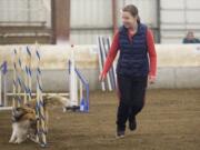 A dog weaves through obstacles as its owner leads it though a course as they take part agility trials held at the Clark County Event Center at the Fairgrounds in Ridgefield on Sunday. The event was held by the Columbia Agility Team.