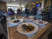 The pan-seared top sirloin, clockwise from foreground, is served with the daily risotto special, the beet salad, the ahi tuna roll and ricotta donuts at Amaro’s Table in downtown Vancouver.