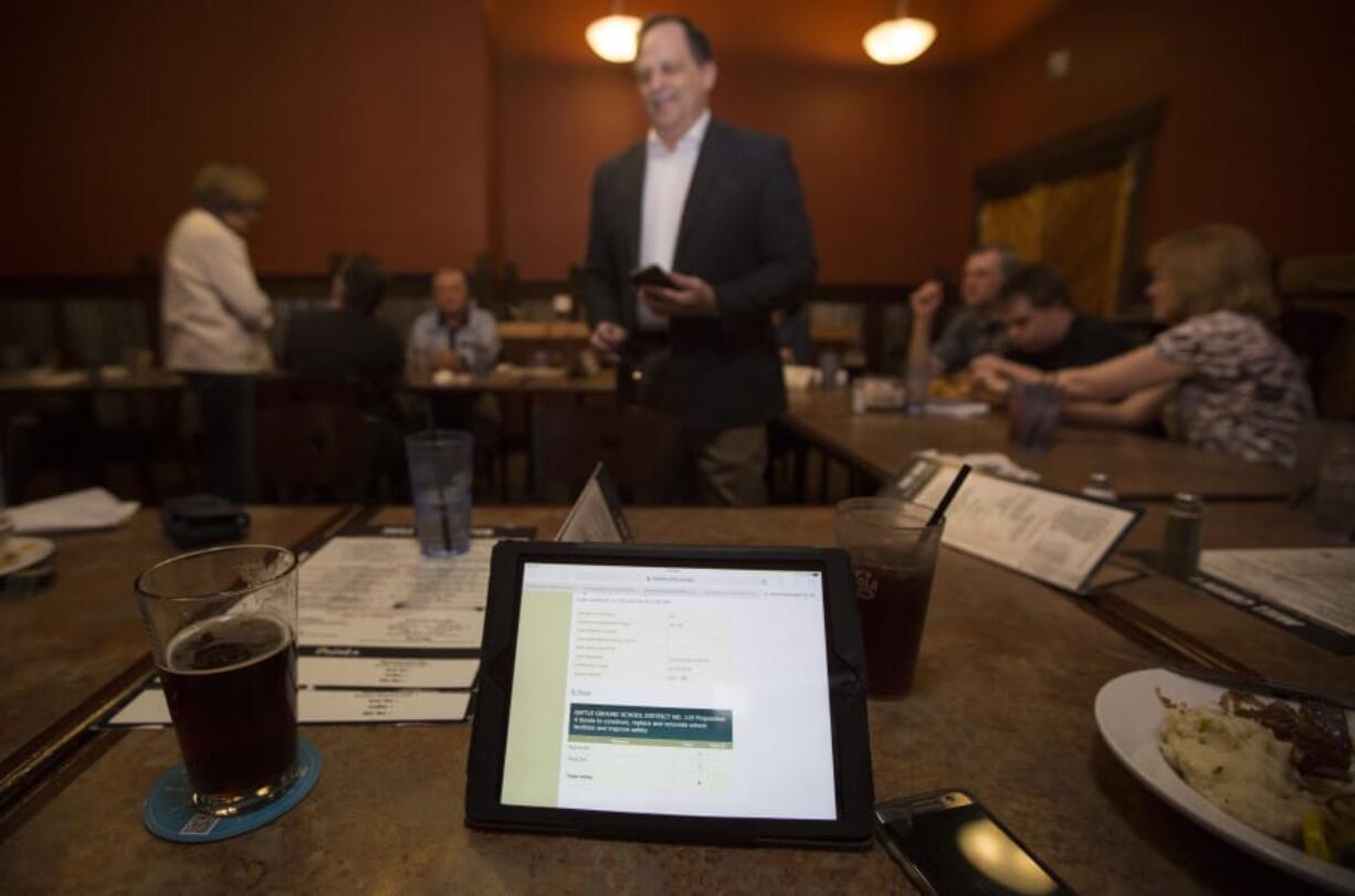 Mark Ross, superintendent of Battle Ground Public Schools, center, and others refresh screens to keep up with election results at a restaurant in Battle Ground on Tuesday night.