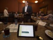 Mark Ross, superintendent of Battle Ground Public Schools, center, and others refresh screens to keep up with election results at a restaurant in Battle Ground on Tuesday night.