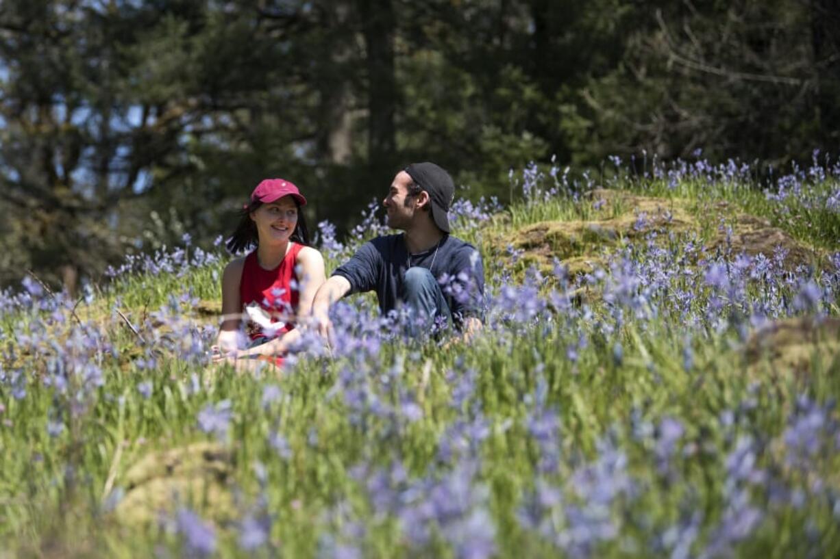 Emma Riggins of Camas, 17, left, and Kevin Coleman of Battle Ground, 18, right, enjoy the field of Camas lilies at Lacamas Lake Regional Park on Monday afternoon. The Camas lilies are now in full bloom just off the Round Lake trail loop. “I love it,” Riggins said.