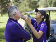 Heritage sophomore Shweta Nand, right, balances a golf ball on her coaches head, Dwight Patterson, in-between holes at the Prairie Invitational at Lewis River Golf Course in Woodland, Wednesday April 25, 2018.