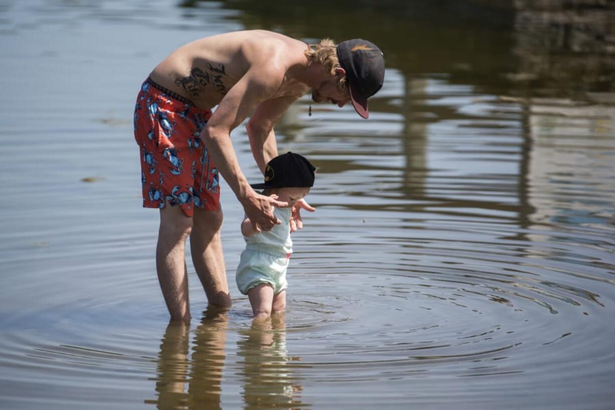 Michael Gile of Vancouver, left, and Hannah Forslund, not pictured, play with their daughter Lily, 1, right, at Klineline Pond in Vancouver in April.