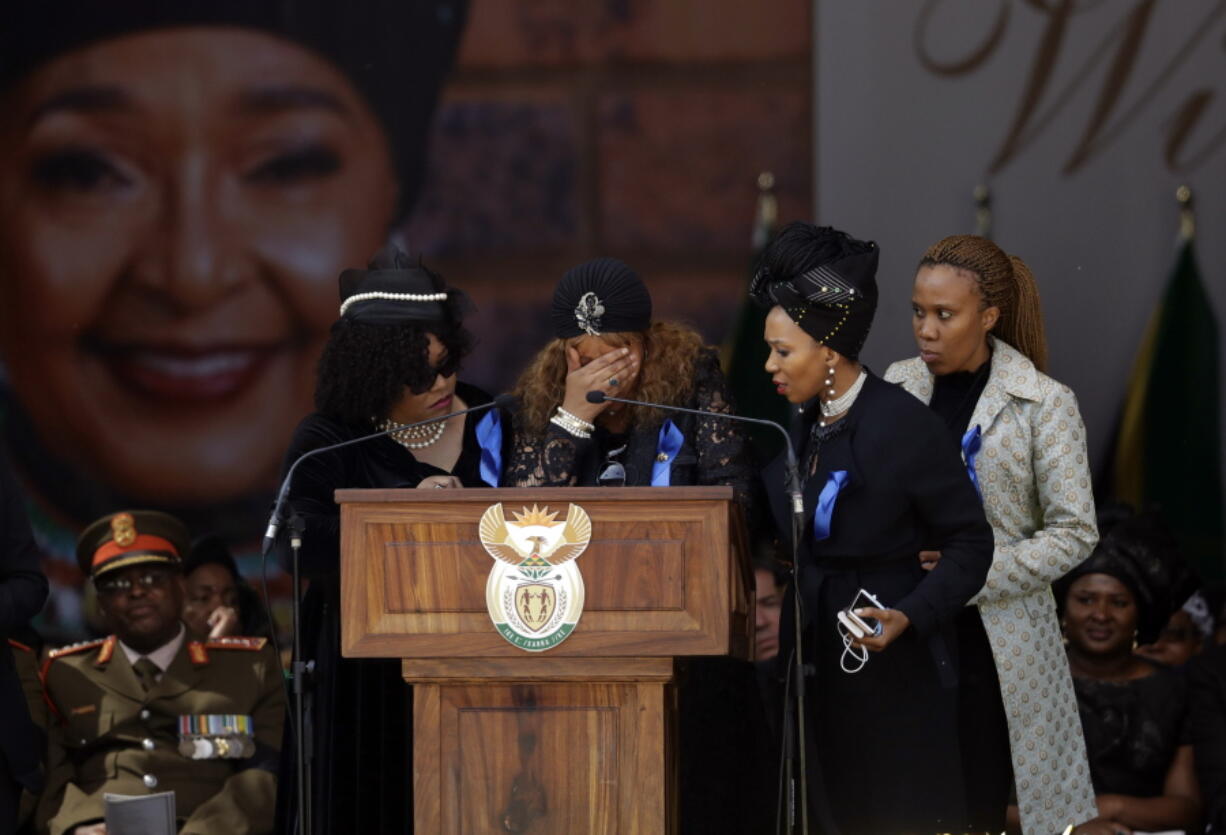 Sisters Zindzi, left, and Zenani, center, at podium, appear on stage to pay tribute to their mother struggle icon Winnie Madikizela-Mandela, backdrop, at her funeral at the Orlando Stadium in Soweto, South Africa, Saturday, April 14, 2018. Madikizela-Mandela died on April 2 at the age of 81.