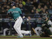 Seattle Mariners’ Mitch Haniger watches his three-run home run in front of Oakland Athletics catcher Jonathan Lucroy during the seventh inning of a baseball game, Friday, April 13, 2018, in Seattle. (AP Photo/Ted S.