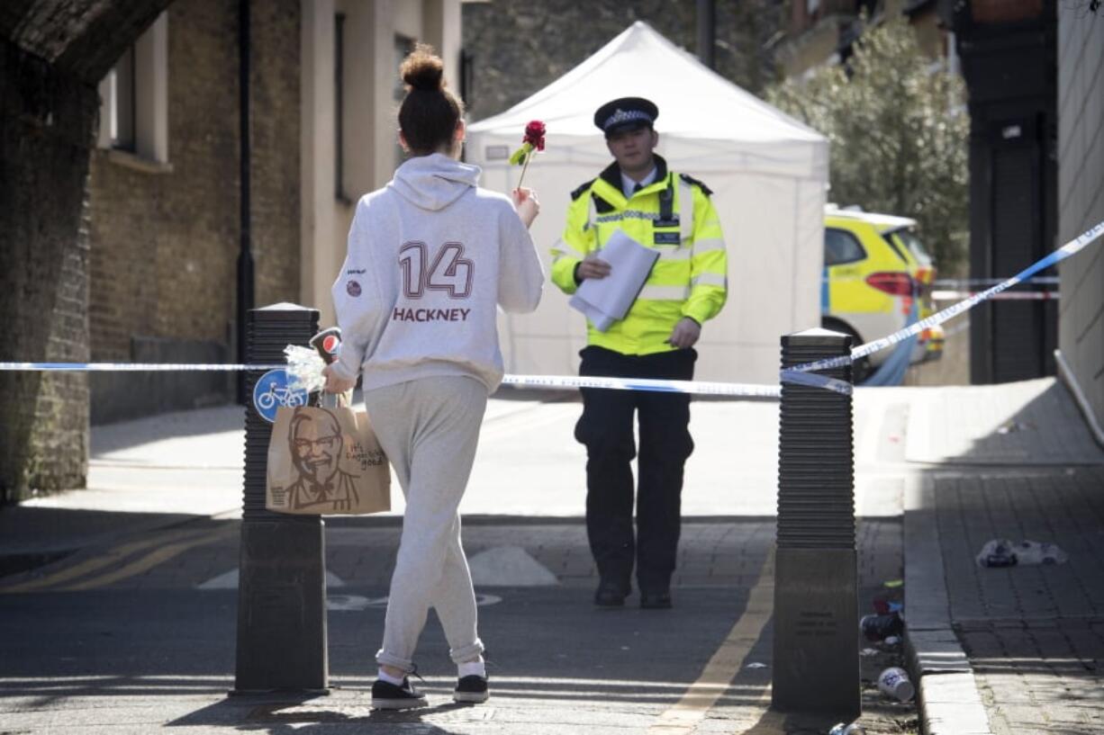 A woman carries a flower to a crime scene in Link Street, Hackney, east London, Thursday April 5, 2018. This week, 18-year-old Israel Ogunsola became London’s 53rd murder victim of 2018. The British capital is being shaken by a spike in deadly violence, much of it involving young people caught up in gang feuds.