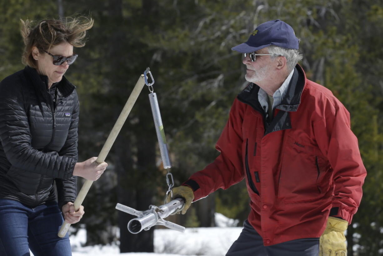 Karla Nemeth, director of the California Department of Water Resources, holds the scale as Frank Gehrke, chief of DWR’s California Cooperative Snow Surveys Program, checks the snow sample weight to determine the water content while conducting the snow survey, Monday, April 2, 2018, near Echo Summit, Calif. Storms hitting at the end of California’s rainy season have eased the state’s plunge back into drought. Water officials trekked to the Sierra Nevada on Monday to measure the late-winter snowpack. Runoff from the snow historically supplies about a third of the state’s water supply.