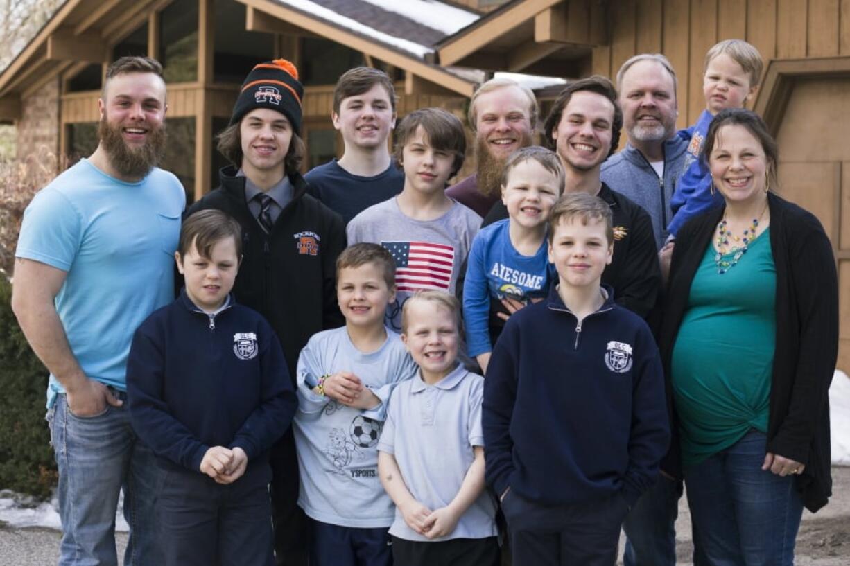 The Schwandt family poses for a portrait in front of their home in Grand Rapids, Mich. The only member not pictured is Brandon, 18. The Schwandt family has 13 sons and have welcomed a 14th into the family. The couple’s latest addition was born Wednesday evening, April 18 five days before the baby’s expected due date.