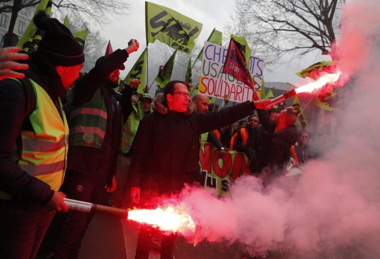 French rail workers carry flares during a demonstration Tuesday in Paris. French unions plan strikes every week through June to protest government plans to eliminate some rail worker benefits.