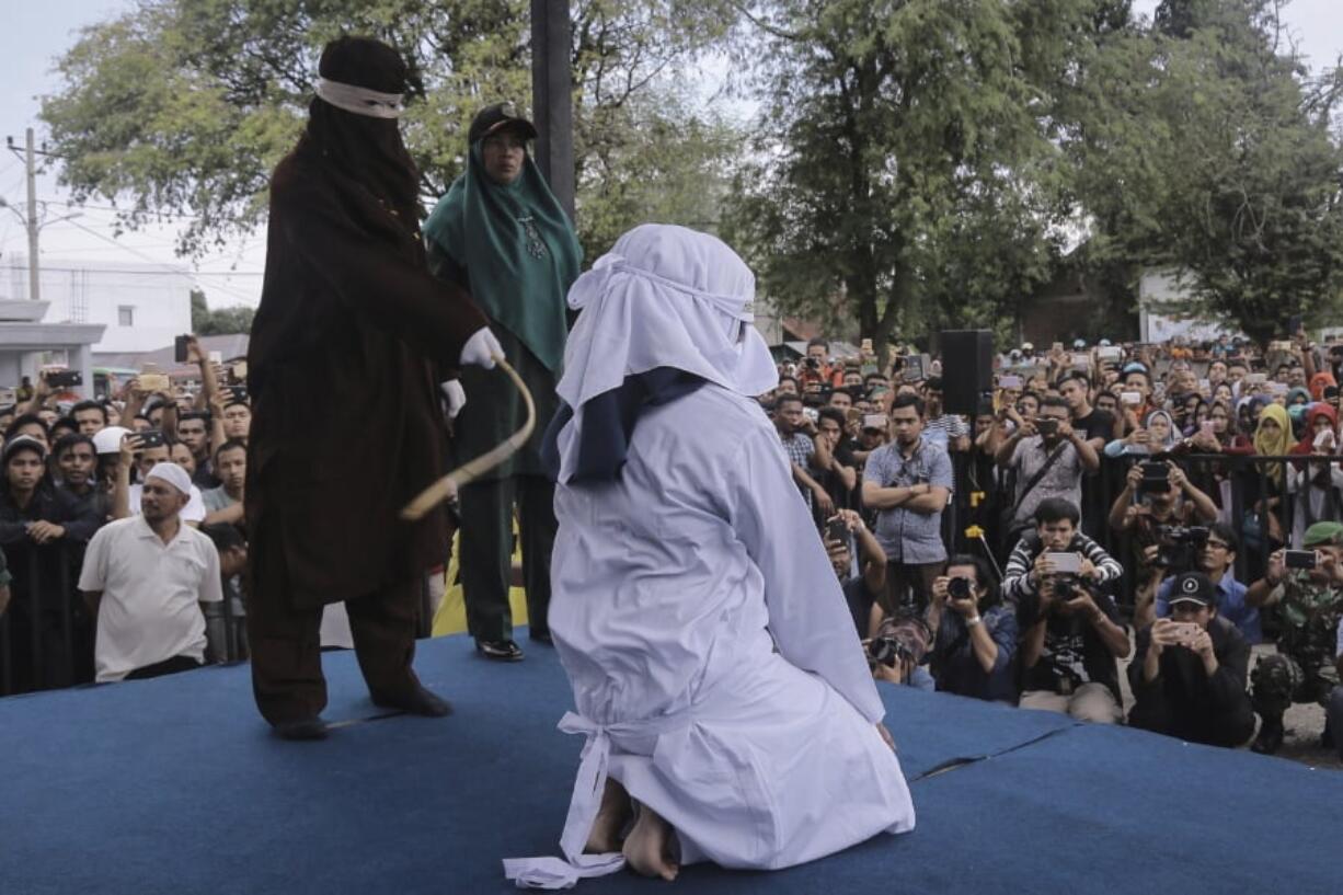 A Shariah law official whips a woman who is convicted of prostitution during a public caning outside a mosque in Banda Aceh, Indonesia, Friday, April 20, 2018. Indonesia’s deeply conservative Aceh province on Friday caned several unmarried couples for showing affection in public and two women for prostitution before an enthusiastic audience of hundreds. The canings were possibly the last to be carried out before large crowds in Aceh after the province’s governor announced earlier this month that the punishments would be moved indoors.