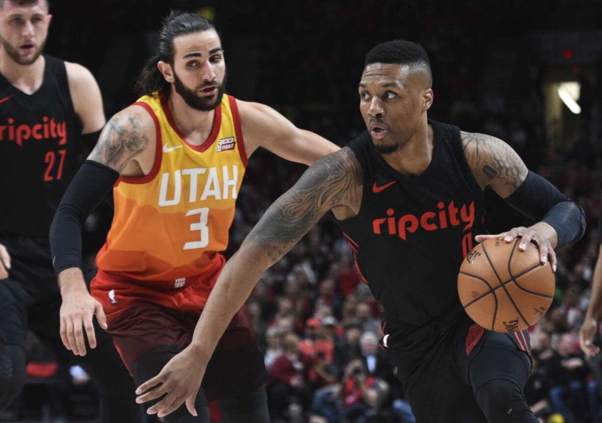 Portland Trail Blazers guard Damian Lillard, right, drives to the basket past Utah Jazz guard Ricky Rubio, left, during the first half of an NBA basketball game in Portland, Ore., Wednesday, April 11, 2018. The Blazers won 102-93.