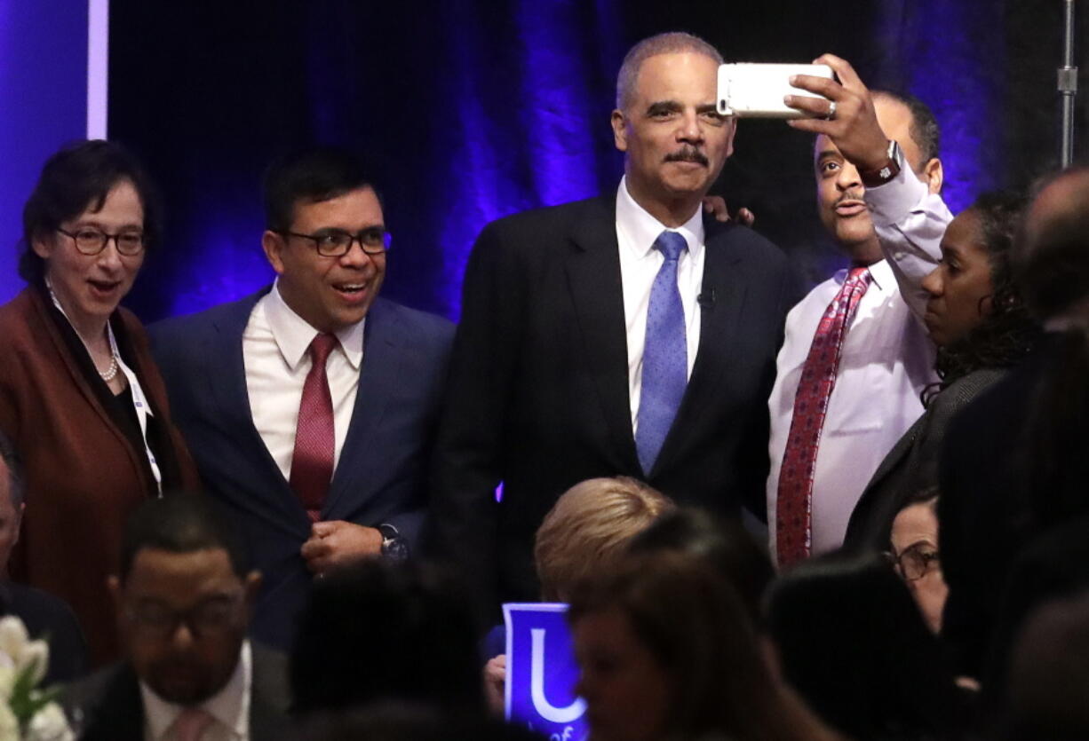 Former Attorney General Eric Holder, second from right, poses for pictures before speaking at the Peabody Hotel Monday, April 2, 2018, in Memphis, Tenn. Holder’s speech is part of the University of Memphis Law Symposium in commemoration of the 50th anniversary of the assassination of the Rev. Martin Luther King Jr.