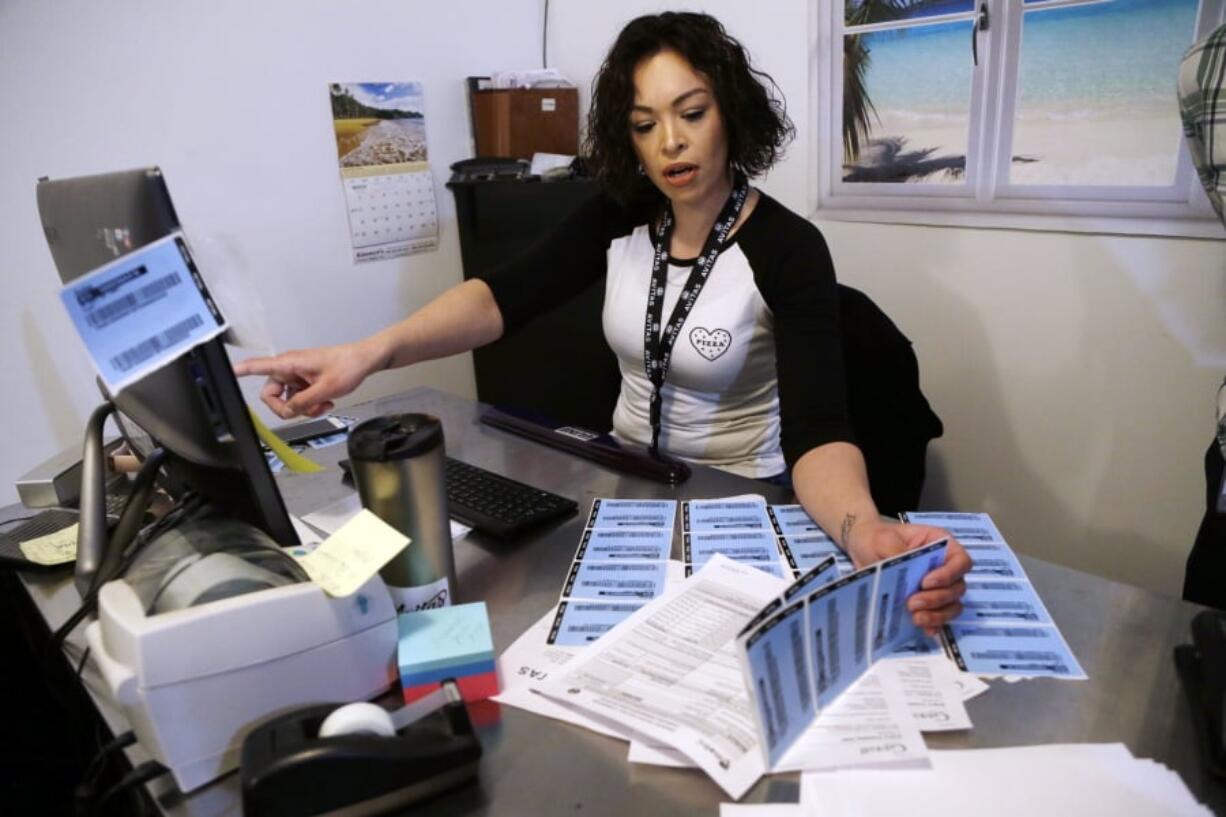 Cecilia Espinoza checks printed product bar codes against their computer database at Avitas marijuana production facility in Salem, Ore.