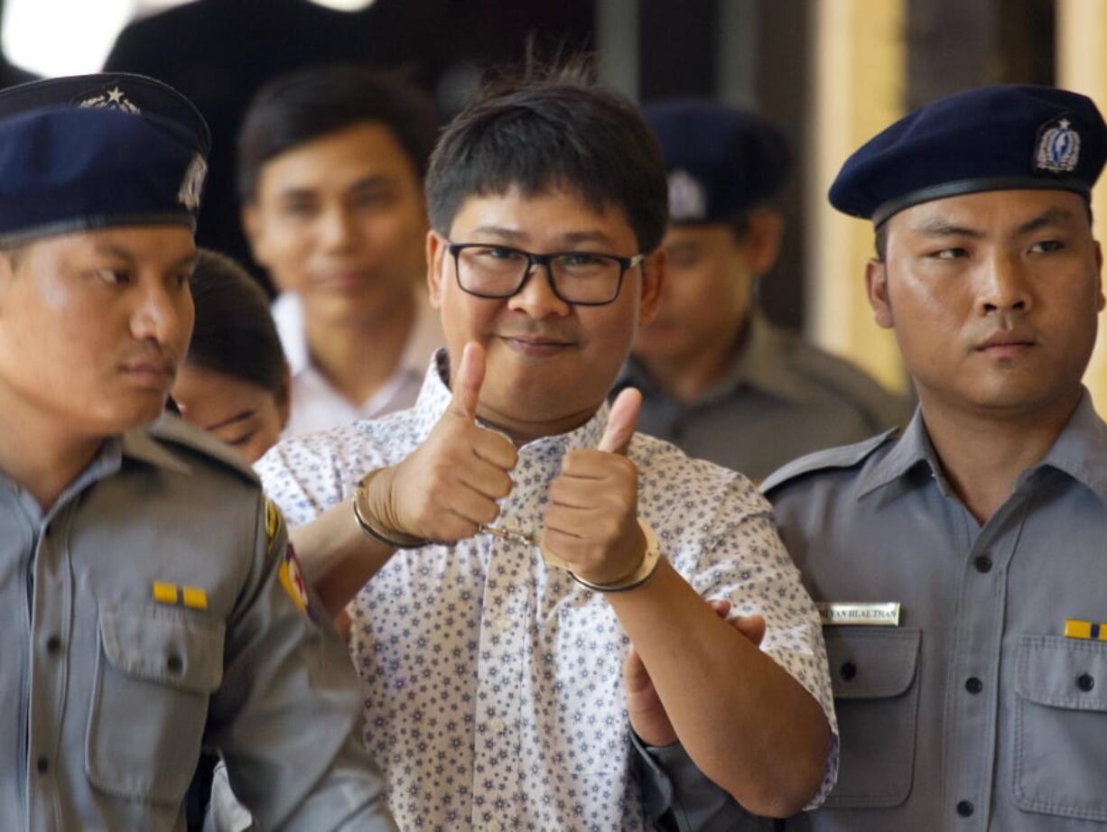 Reuters journalist Wa Lone, center, gives a thumbs-up sign as he is escorted by police Friday at court in Yangon, Myanmar.