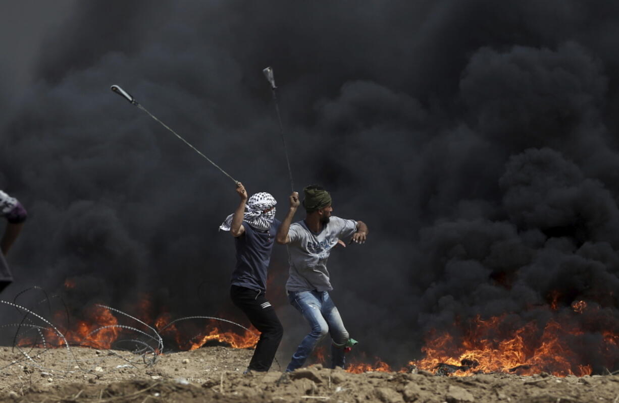 Palestinian protesters hurl stones at Israeli troops amid black smoke from burning tires Friday during a protest at the Gaza Strip’s border with Israel.