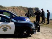 FILE - In this March 28, 2018, file photo, California Highway Patrol officers and deputy sheriffs from Mendocino and Alameda counties gather after a search for three missing children at the site where the bodies of Jennifer and Sarah Hart and three of their adopted children were recovered two days earlier, after the family’s SUV plunged over a cliff at a pullout on the Pacific Coast Highway near Westport, Calif. Three of the children, Devonte Hart, 15, Hannah Hart, 16, and Sierra Hart, 12, have not been found. Authorities say a woman who drove off California cliff last month in an SUV carrying her wife and children was drunk. California Patrol Capt. Bruce Carpenter said Friday, April 13, 2018, that toxicology tests found Jennifer Hart had an alcohol level of .102. California drivers are considered drunk with a level of 0.08 or higher. Authorities don’t know who was at the wheel at the time of the accident.