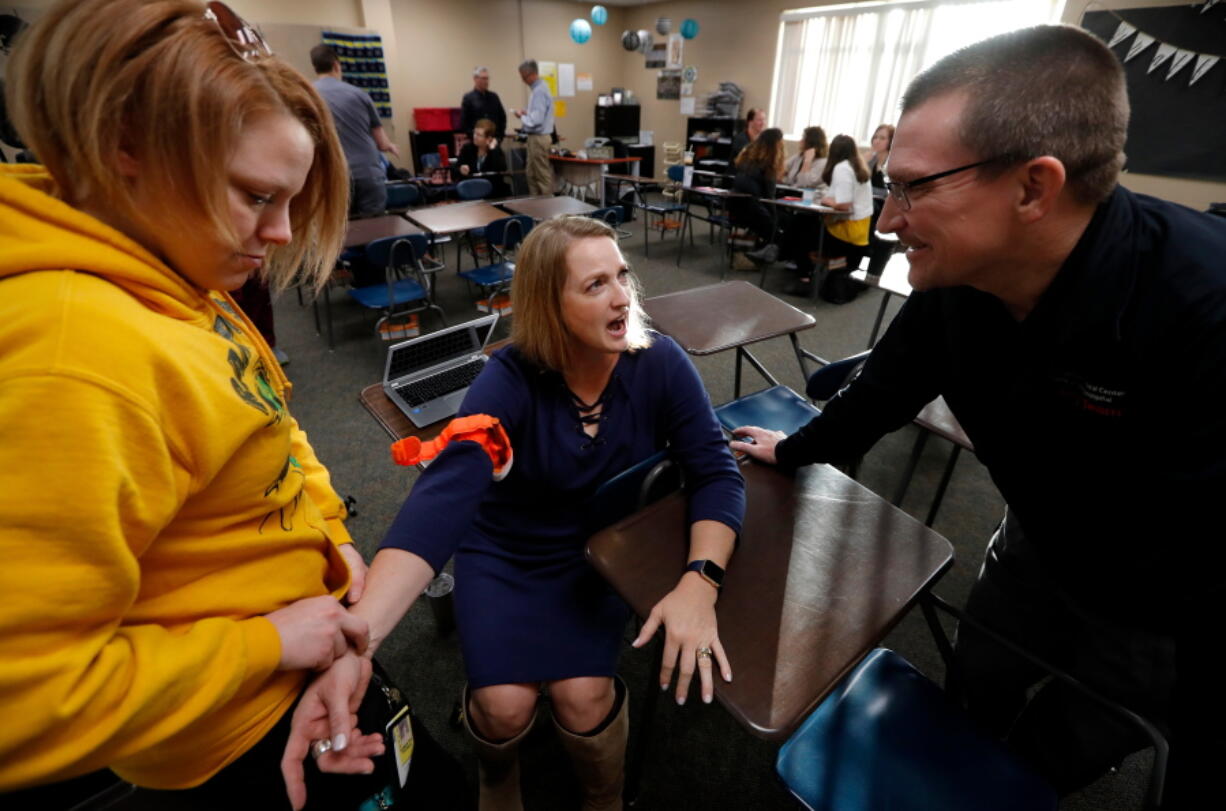 Dr. Richard Sidwell, right, talks with Mary Owens, center, and Samantha Wing during a medical training session for teachers and staff at Southeast Polk High School in Pleasant Hill, Iowa. With school shootings a regular occurrence, educators across the country are learning techniques to help victims survive by stemming blood loss. A Connecticut doctor helped launch the effort, dubbed Stop the Bleed. The nonprofit program has spread to all 50 states, with more than 125,000 teachers, counselors and school administrators learning skills.