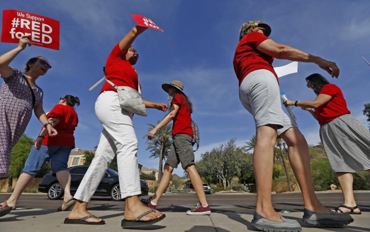 Arizona teachers protest their low pay and school funding in front of a local radio station waiting for Republican Gov. Doug Ducey to show up for a live broadcast Tuesday in Phoenix. Arizona teachers are threatening a statewide walkout, following the lead of educators in other states. (AP Photo/Ross D.