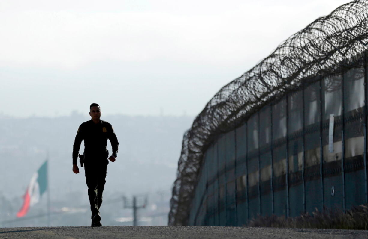 Border Patrol agent Eduardo Olmos walks near the secondary fence separating Tijuana, Mexico, background, and San Diego in San Diego. California Gov. Jerry Brown agreed Wednesday, April 11, 2018, to deploy 400 National Guard troops at President Donald Trump’s request, but not all will head to the U.S.-Mexico border as Trump wants and none will enforce federal immigration enforcement.