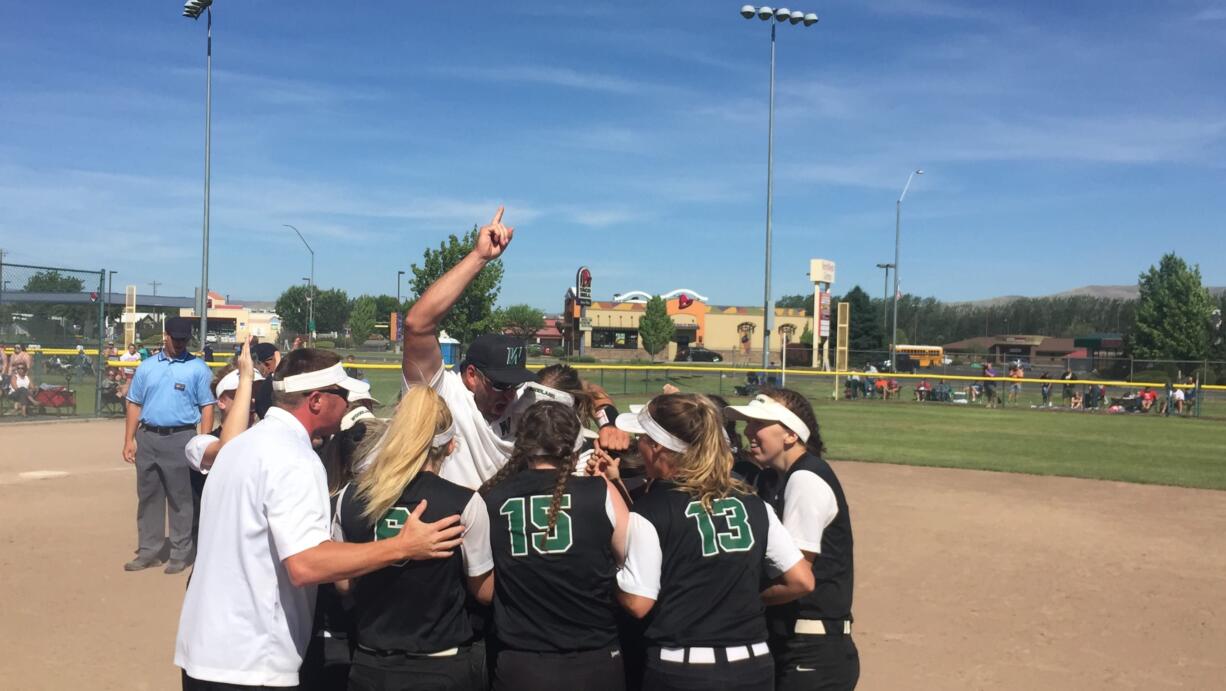 The Woodland softball team swarms around coach Tom Christensen after winning the Class 2A state softball championship Saturday in Selah.