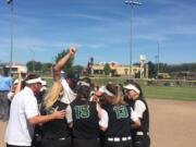 The Woodland softball team swarms around coach Tom Christensen after winning the Class 2A state softball championship Saturday in Selah.