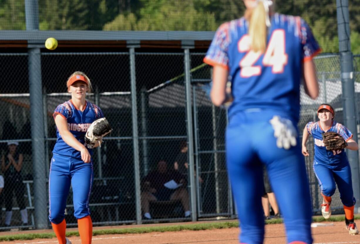 Ridgefield’s Kaia Oliver tosses the game-winning out to Karli Oliver as Calli Martin (right) begins to celebrate the Spudders’ 4-3 win over Woodland in 10 innings.