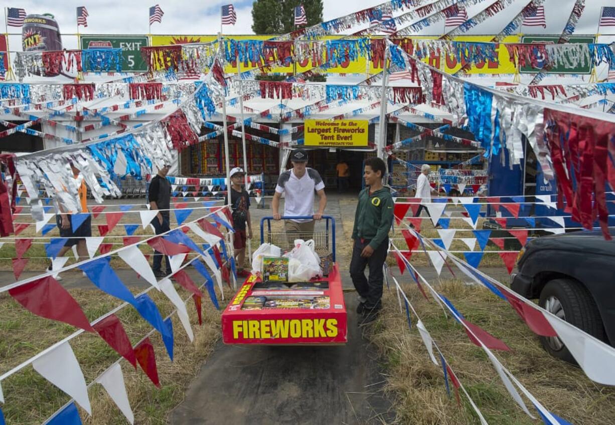 Noah Vallembois, left, lends a hand to Brendon Abbott and Rashad Dixon as they join family and friends during a shopping trip to TNT Fireworks in unincorporated Clark County last summer. The county is asking residents to complete a survey on fireworks use.