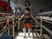 Austin Justin walks in front of his mom, Tabitha Fich, between parallel bars with his new RGO braces at his weekly physical therapy appointment at Shriners Hospitals for Children in Portland in April. “Every week when we go to therapy, his therapist always compliments how well he’s progressing and how fast he’s coming along, because it takes years for kids to be able to even get used to the RGOs,” Fich said. “Austin is just rocking through it.