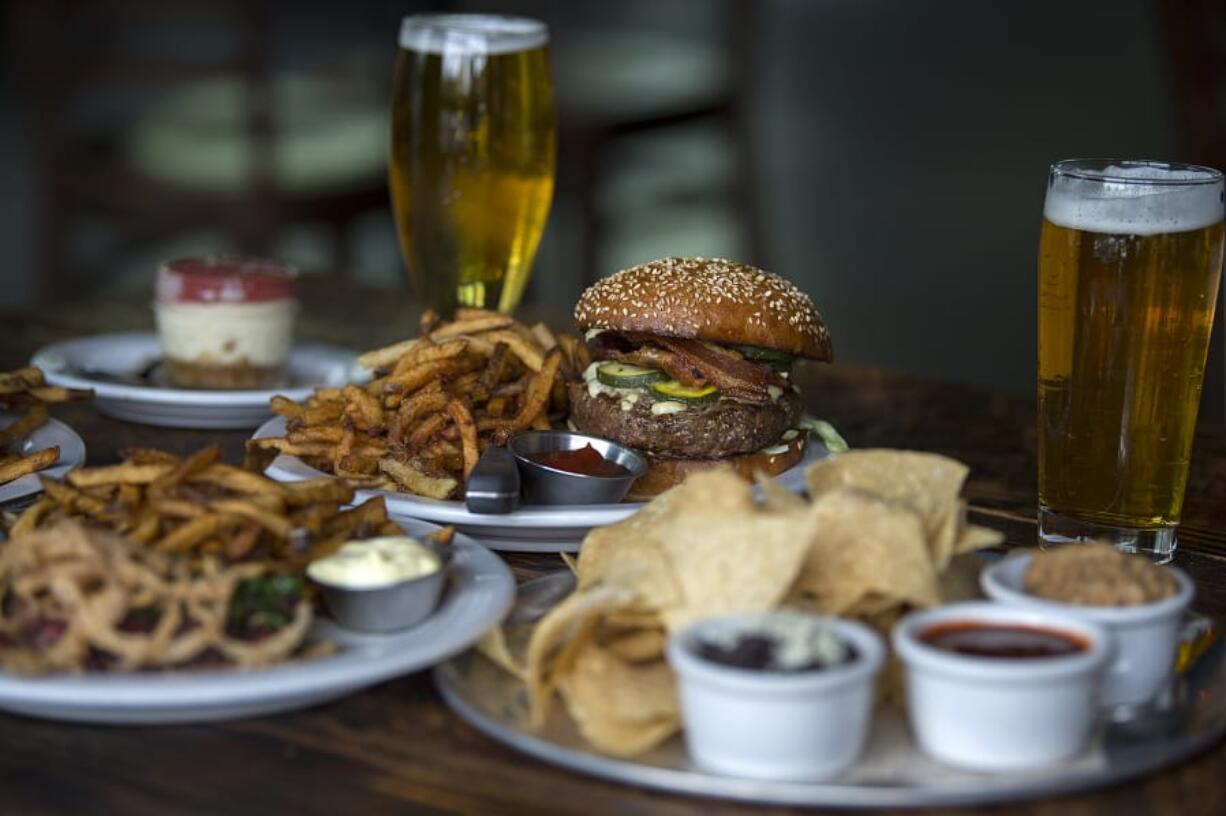 Cheesecake, from left, is served with a burger with blue cheese and bacon and Chips N’ Dips at Grains of Wrath Brewing in Camas.