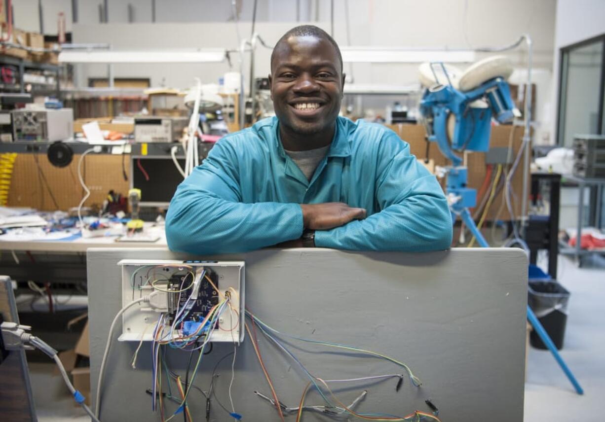 Komivi Akengue, 26, leans on an interactive soccer wall he helped create at ControlTek in Vancouver. The soccer wall, which Akengue worked on in his capstone class at Washington State University Vancouver, provides light-up targets for soccer players and tracks the speed of the ball. Akengue, who is originally from Togo, will be graduating Saturday from WSU Vancouver with a degree in electrical engineering.