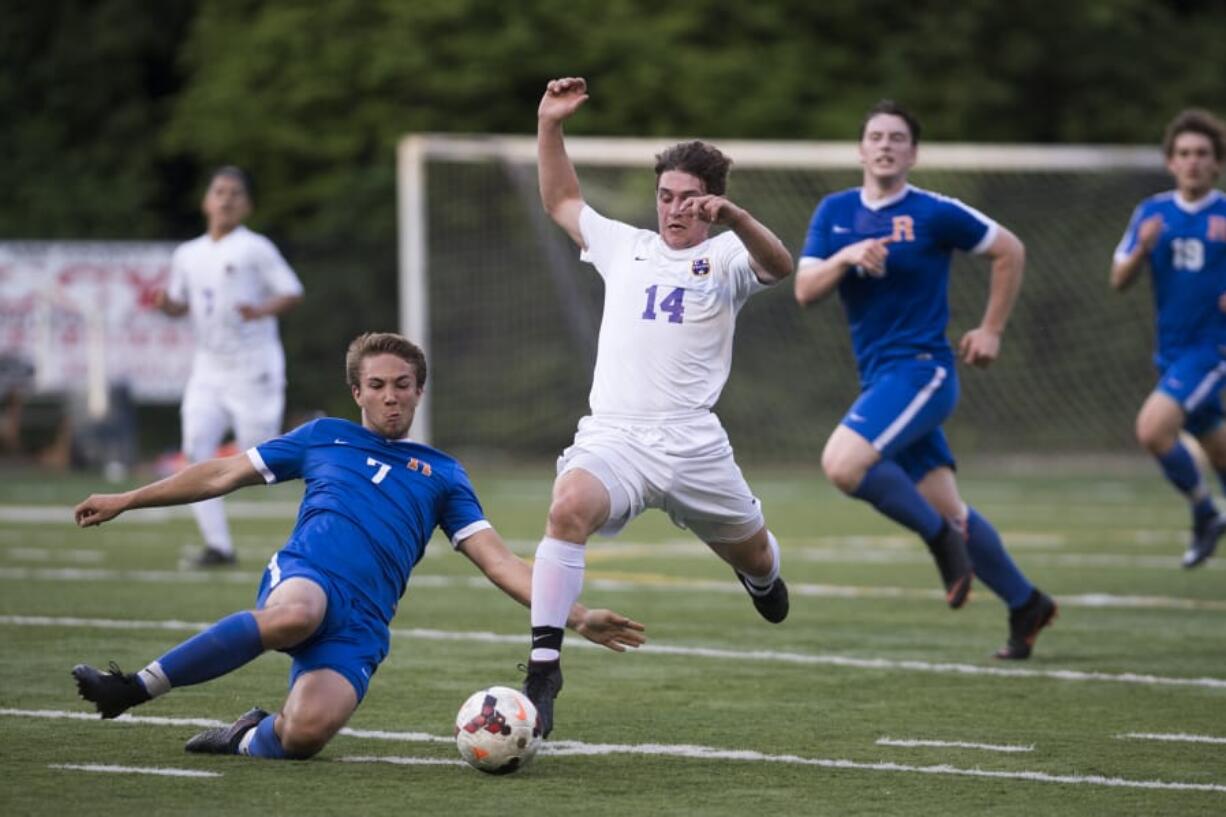 Ridgefield’s Jonathan Flury (7) slide tackles Columbia River’s Jake Connop (14).