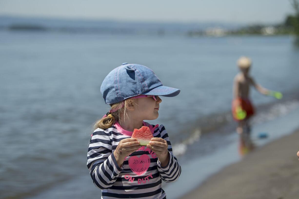 Everly Vanderlist, 3, of Vancouver stays cool in her shades as she feasts on a snack of watermelon while relaxing with her mom and dog at Wintler Park on Monday afternoon.