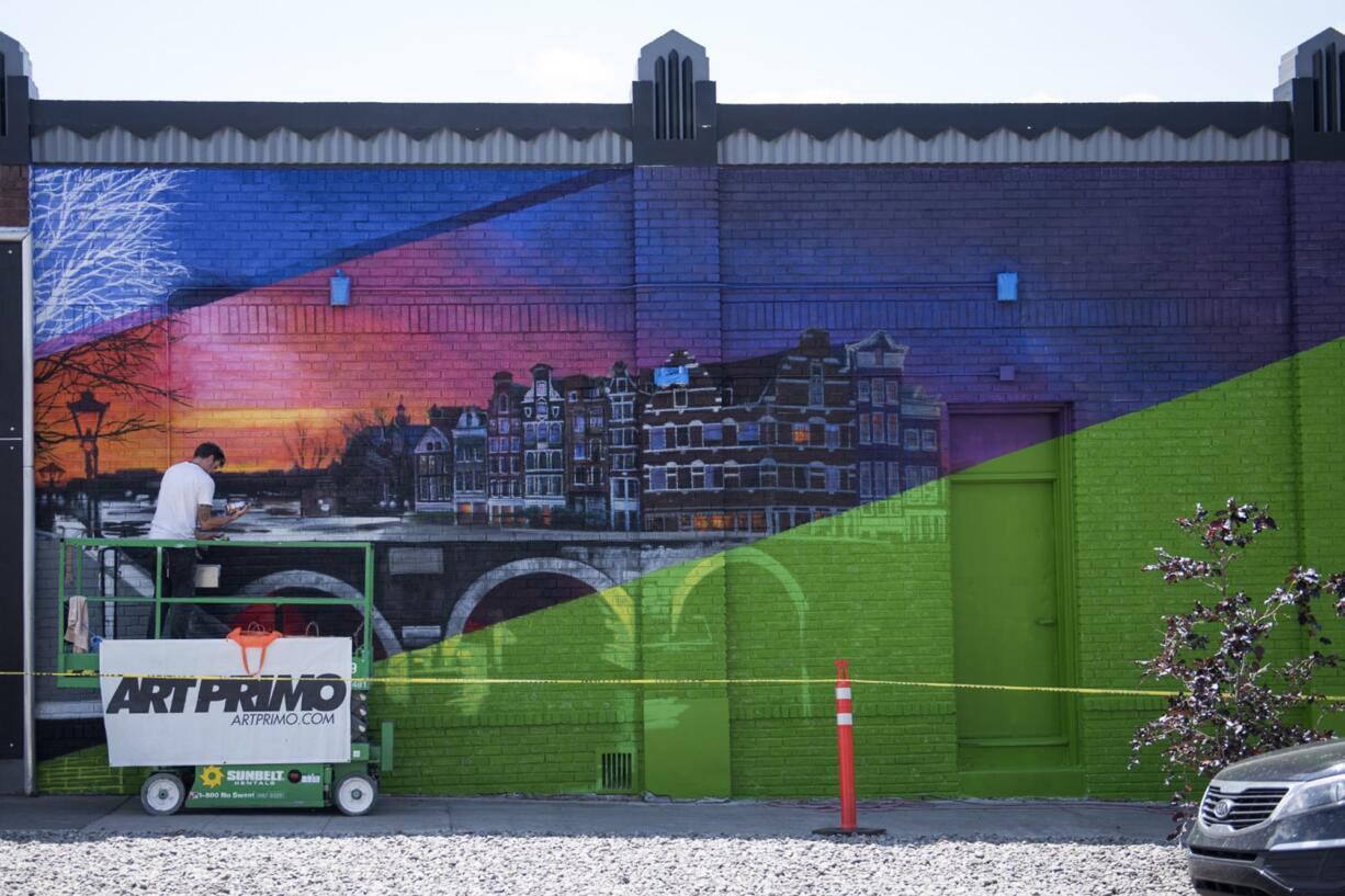 Seattle-based artist Jeff Jacobson, "Weirdocult", puts the finishing touches on a mural outside Main Street Marijuana in Vancouver on Thursday, May 24, 2018.  Jacobson arrived last weekend to start the mural he's titled, "Electric Amsterdam." He describes the piece of art as post-internet hyper realism. It's a take on classic realism and something that feels historical for uptown, he said.