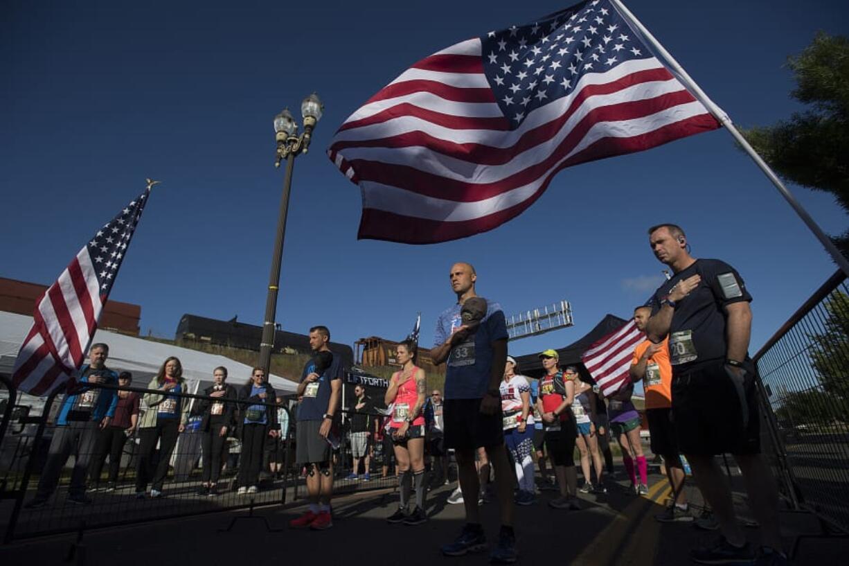 Amanda Cowan/The Columbian Participants in the Race to Remember half marathon pause for the playing of the National Anthem before taking off from the starting line at Veterans of Foreign Wars Memorial Plaza on Monday morning. At least 150 people came out to take part in the annual event honoring fallen servicemembers.