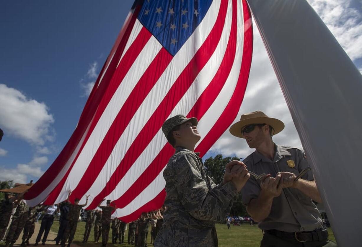 Wyatt Moody, 14, center, of the Battle Ground Air Force JROTC helps Fort Vancouver National Historic Site facility manager Alex Patterson as they join the effort to raise the garrison flag during the annual Memorial Day Observance on Monday morning.