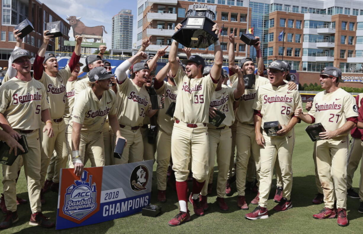 Florida State’s Cal Raleigh (35) lifts the trophy following an Atlantic Coast Conference NCAA college baseball tournament championship game against Louisville in Durham, N.C., Sunday, May 27, 2018. Florida State won 11-8.