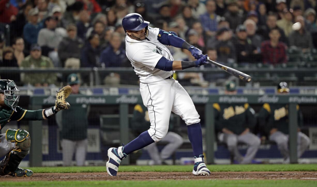 Seattle Mariners' Nelson Cruz hits a three-run home run in front of Oakland Athletics catcher Jonathan Lucroy during the fifth inning of a baseball game Tuesday, May 1, 2018, in Seattle.