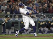 Seattle Mariners' Nelson Cruz hits a three-run home run in front of Oakland Athletics catcher Jonathan Lucroy during the fifth inning of a baseball game Tuesday, May 1, 2018, in Seattle.