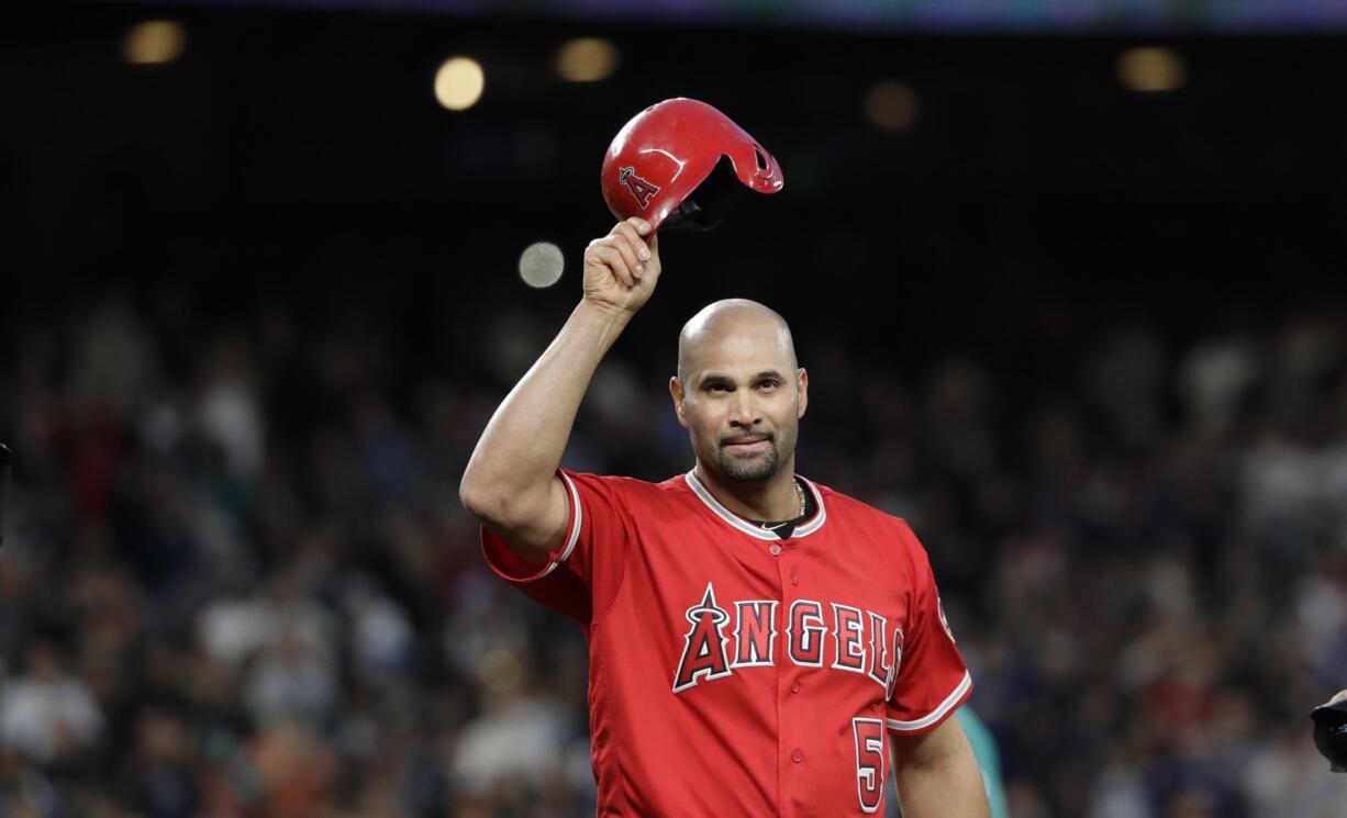 Los Angeles Angels' Albert Pujols waves his helmet to fans after hitting a single against the Seattle Mariners in the fifth inning of a baseball game Friday, May 4, 2018, in Seattle. The hit was Pujols' 3,000th of his career.