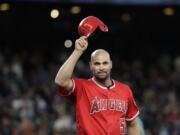 Los Angeles Angels' Albert Pujols waves his helmet to fans after hitting a single against the Seattle Mariners in the fifth inning of a baseball game Friday, May 4, 2018, in Seattle. The hit was Pujols' 3,000th of his career.